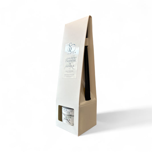 Angled view of Golden Cashmere & Vanilla 100ml odour eliminating reed diffuser in white box, showing label and black reeds, handmade in London