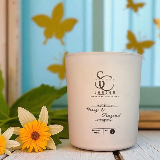 Luxury soy wax candle in glass container next to flowers on a wooden table