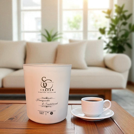 luxury scented candle in a white frosted glass container on a coffee table with a cup of coffee