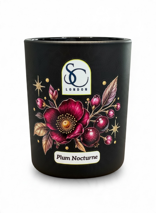 Close-up of Plum Nocturne 9cl winter candle showing a deep burgundy flower, rich plum-coloured berries, gold leaves and delicate stars on a black glass vessel.