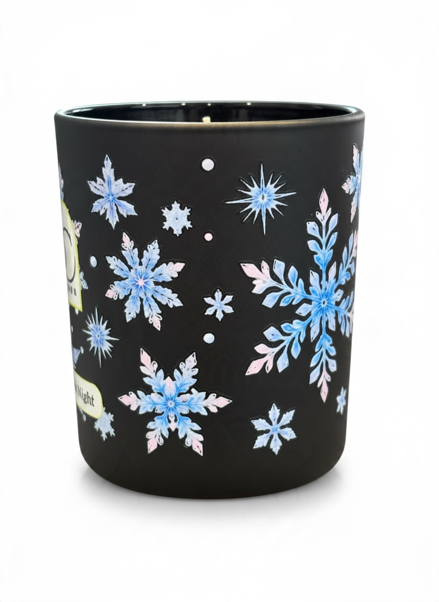 Close-up of the Twelfth Night 30cl winter candle showing intricate icy blue, silver and soft pink snowflake artwork wrapping around the black glass vessel.