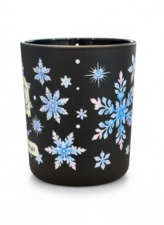 Close-up of the Twelfth Night 30cl winter candle showing intricate icy blue, silver and soft pink snowflake artwork wrapping around the black glass vessel.