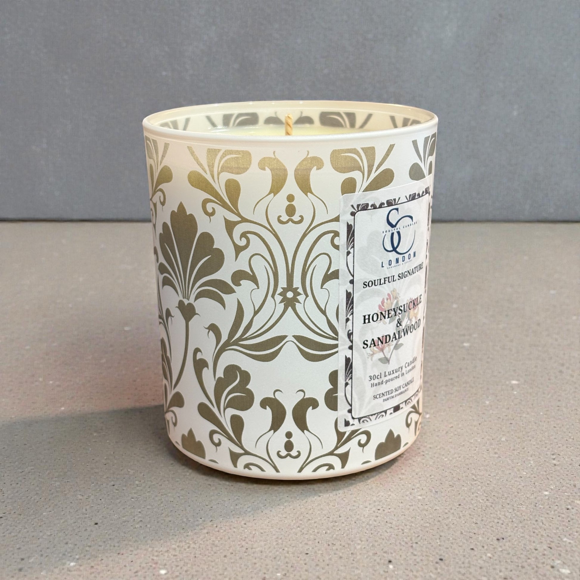 Decorative candle with intricate patterns and a label on a gray surface