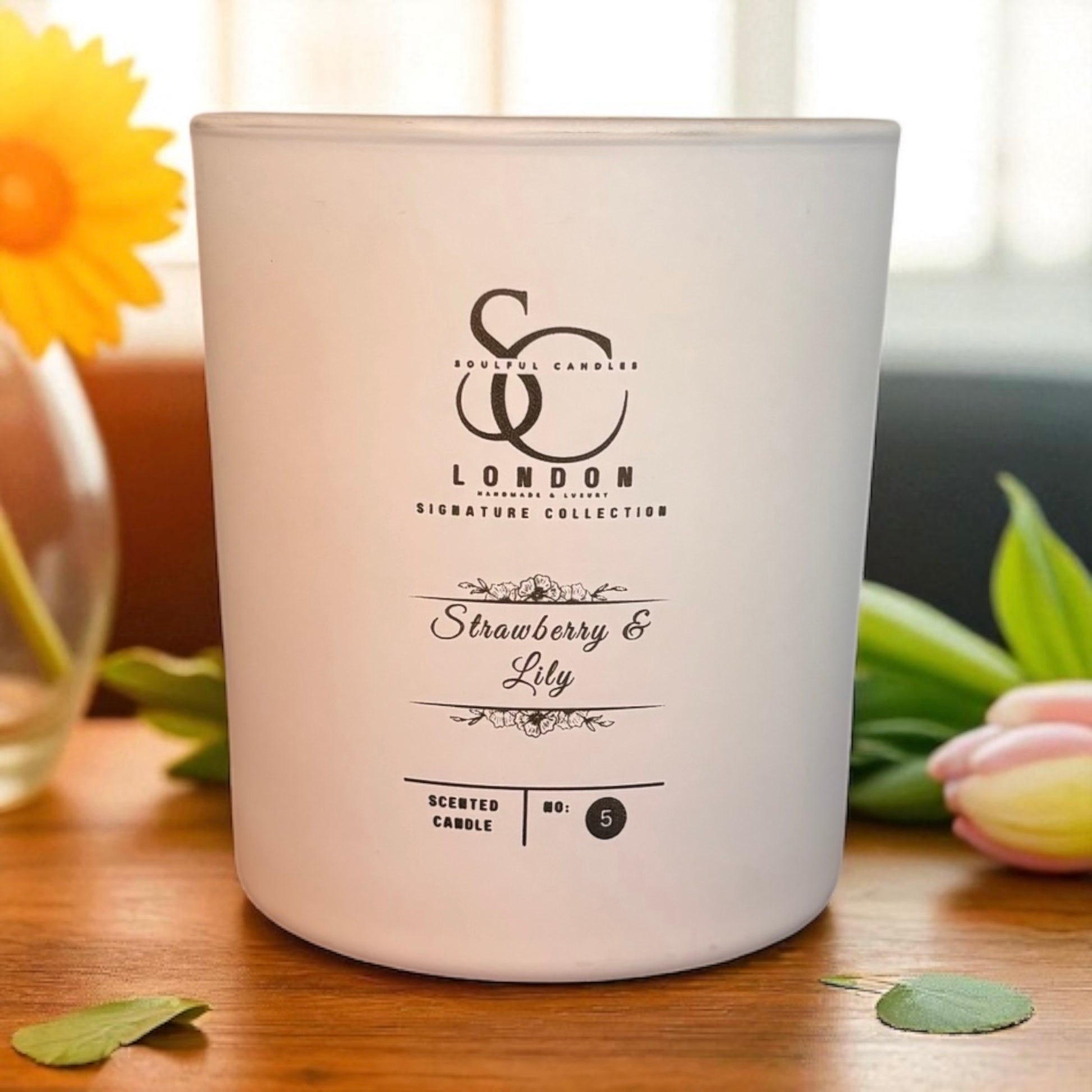 Scented candle with 'SC London' branding on a wooden surface with flowers in the background