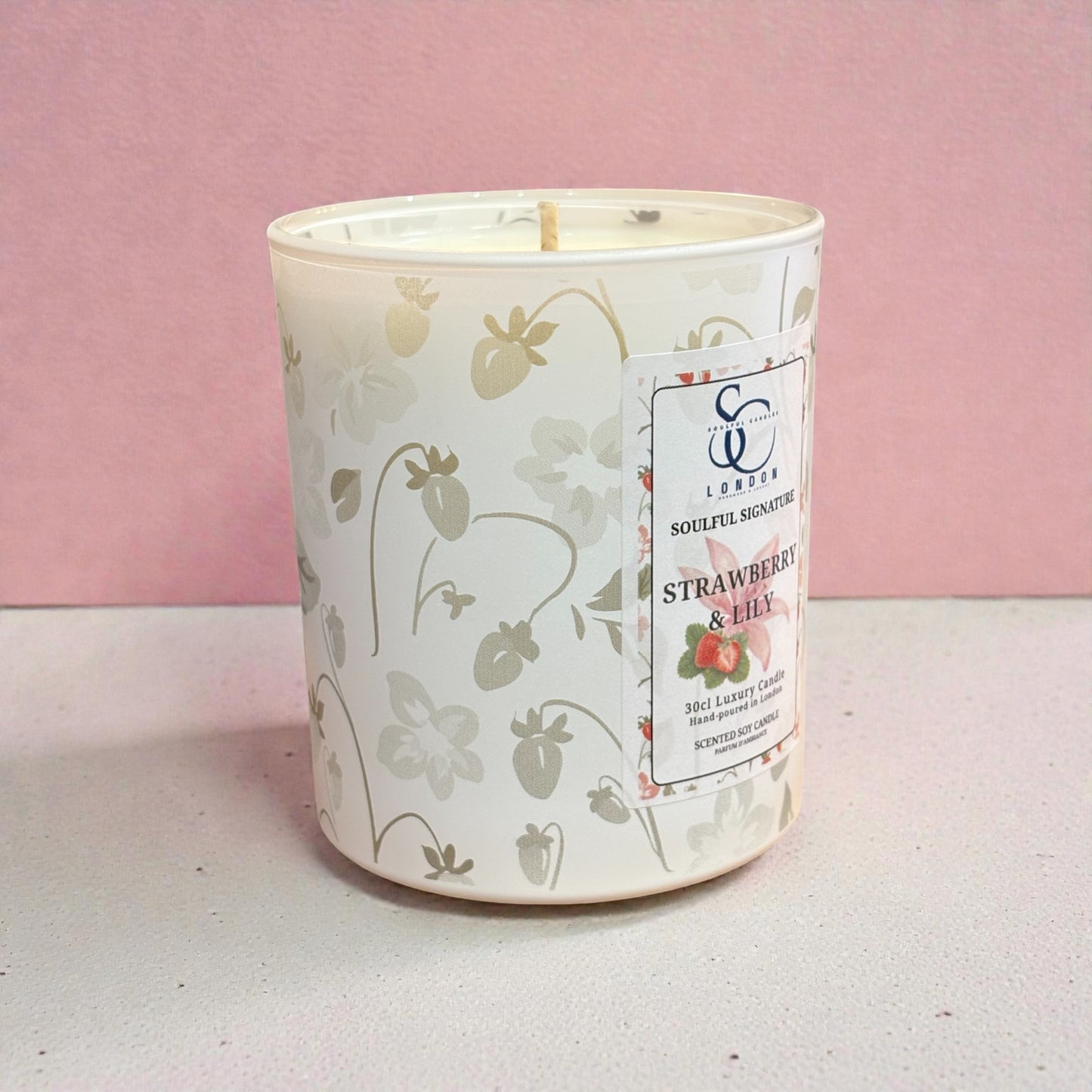 Candle with strawberry design and label on a pink background
