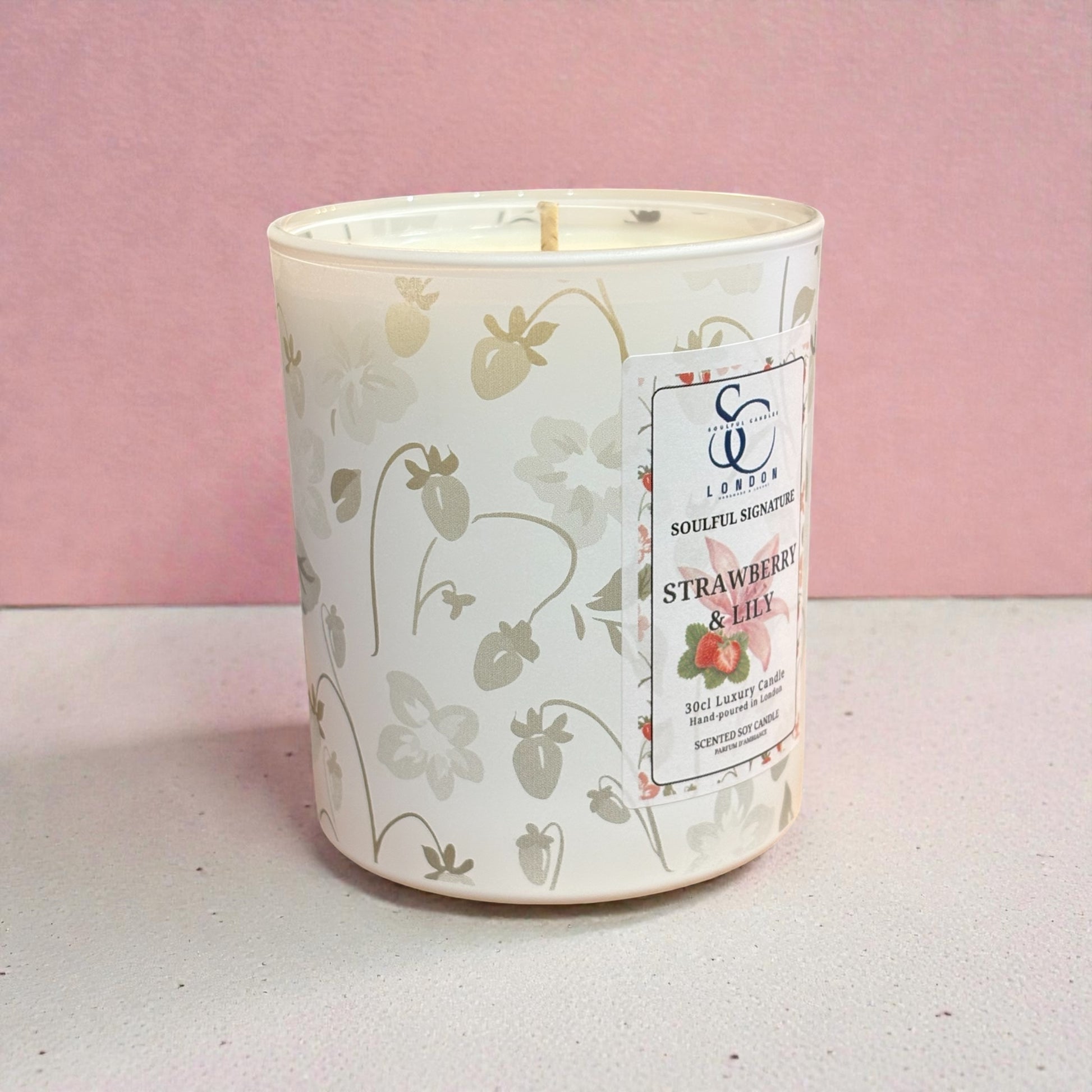Candle with strawberry design and label on a pink background
