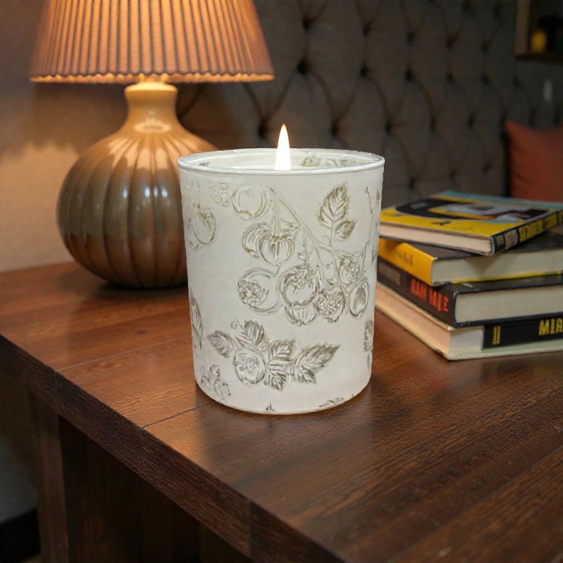 Lit Blackcurrant & Truffle soy candle in botanical illustrated glass on bedside table