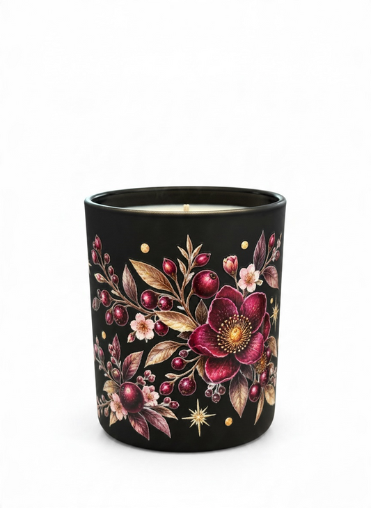 Close-up of Plum Nocturne 30cl winter candle showing a deep burgundy flower surrounded by berries, botanical leaves and delicate gold stars on a black glass vessel.
