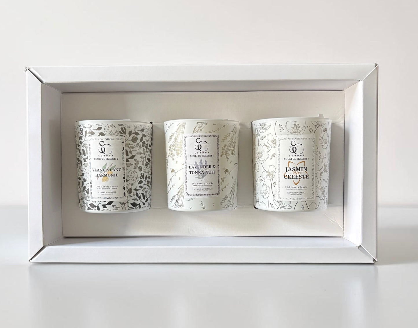 Three candles in a decorative box with floral designs on labels.