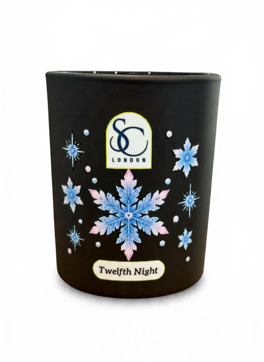 Close-up of Twelfth Night 9cl winter candle showing a large icy blue and soft pink snowflake with smaller decorative snowflakes on a black glass vessel.